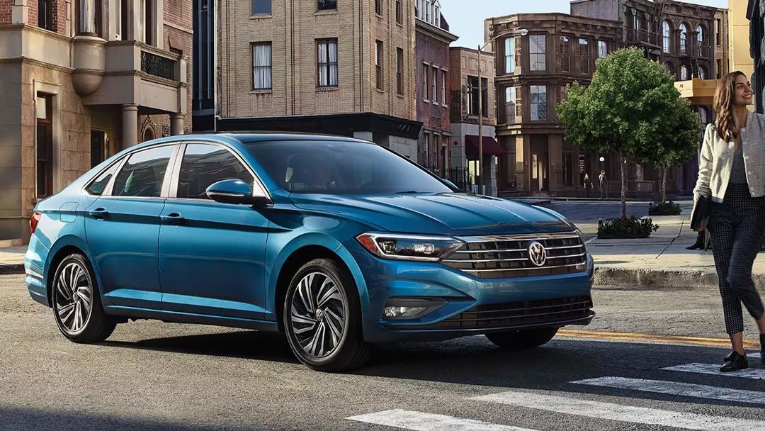 The 2021 VW Jetta Execline silk blue metallic stop in front of the pedestals crossing the street