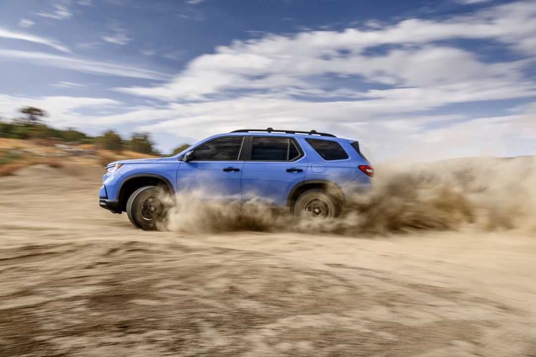 Side view of the 2023 Honda Pilot in action on sandy dirt.