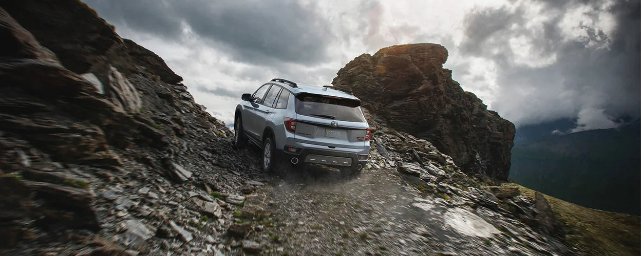 Rear view of the 2023 Honda Passport SUV going uphill on a mountain.