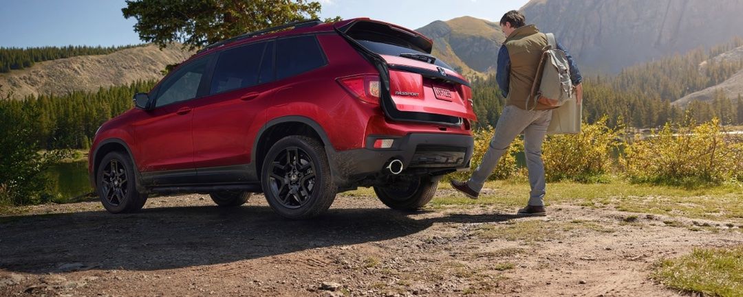 A man opens the boot of his Honda Passport 2024 with automatic foot detection under the vehicle.