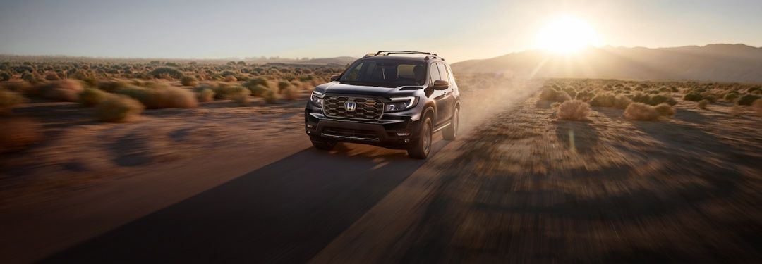 Honda Passport driving along a dirt road at sunset.