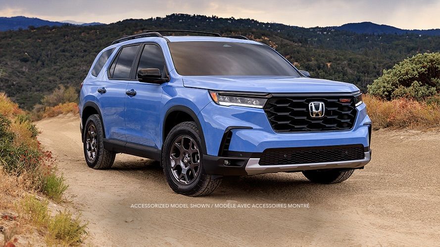 3/4 front view of the Honda Pilot 2025 parked on a dirt road.