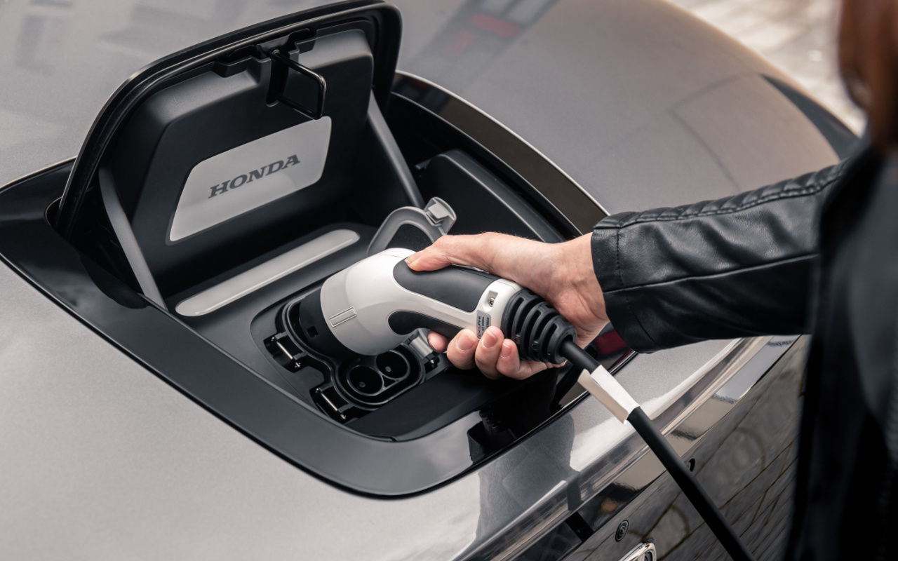 vue d'une personne qui branche son véhicule à une borne de recharge électrique