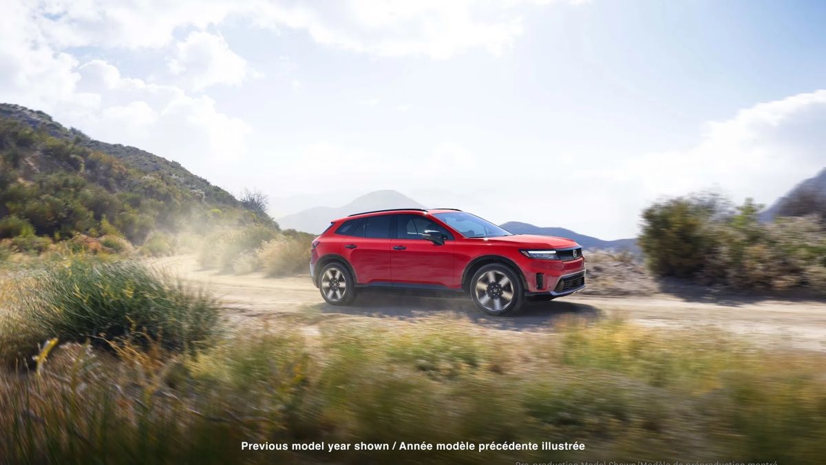 Honda Prologue 2025 rouge circulant sur un chemin de terre en montagne, démontrant ses capacités polyvalentes et sa traction intégrale.