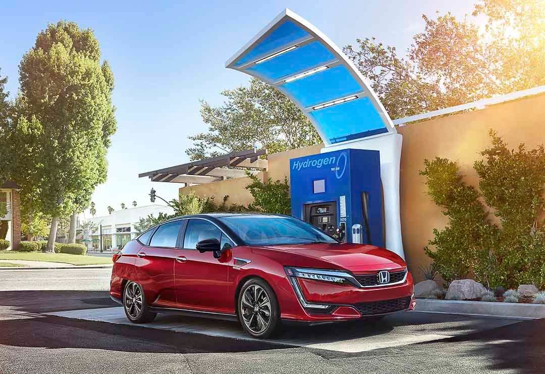 A red plug-in Honda Clarity plugged into a hydrogen refueling station