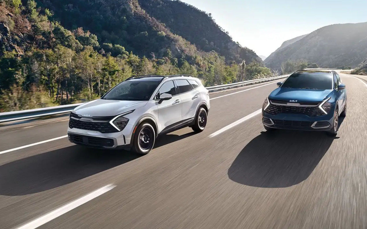 vue latérale avant d'un duo de Kia Sportage 2025 sur une route de montagne