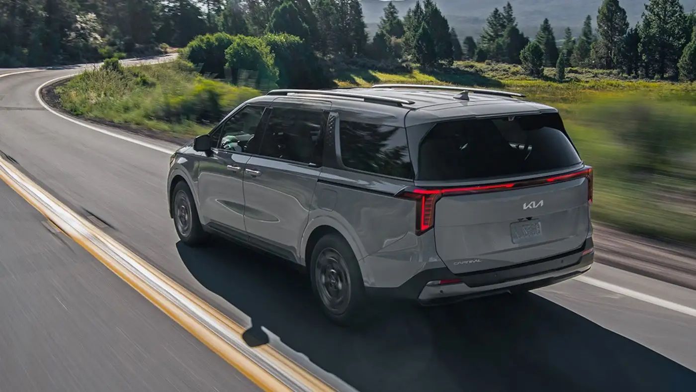 vue latérale arrière d'une Kia Carnival 2025 sur une route de campagne