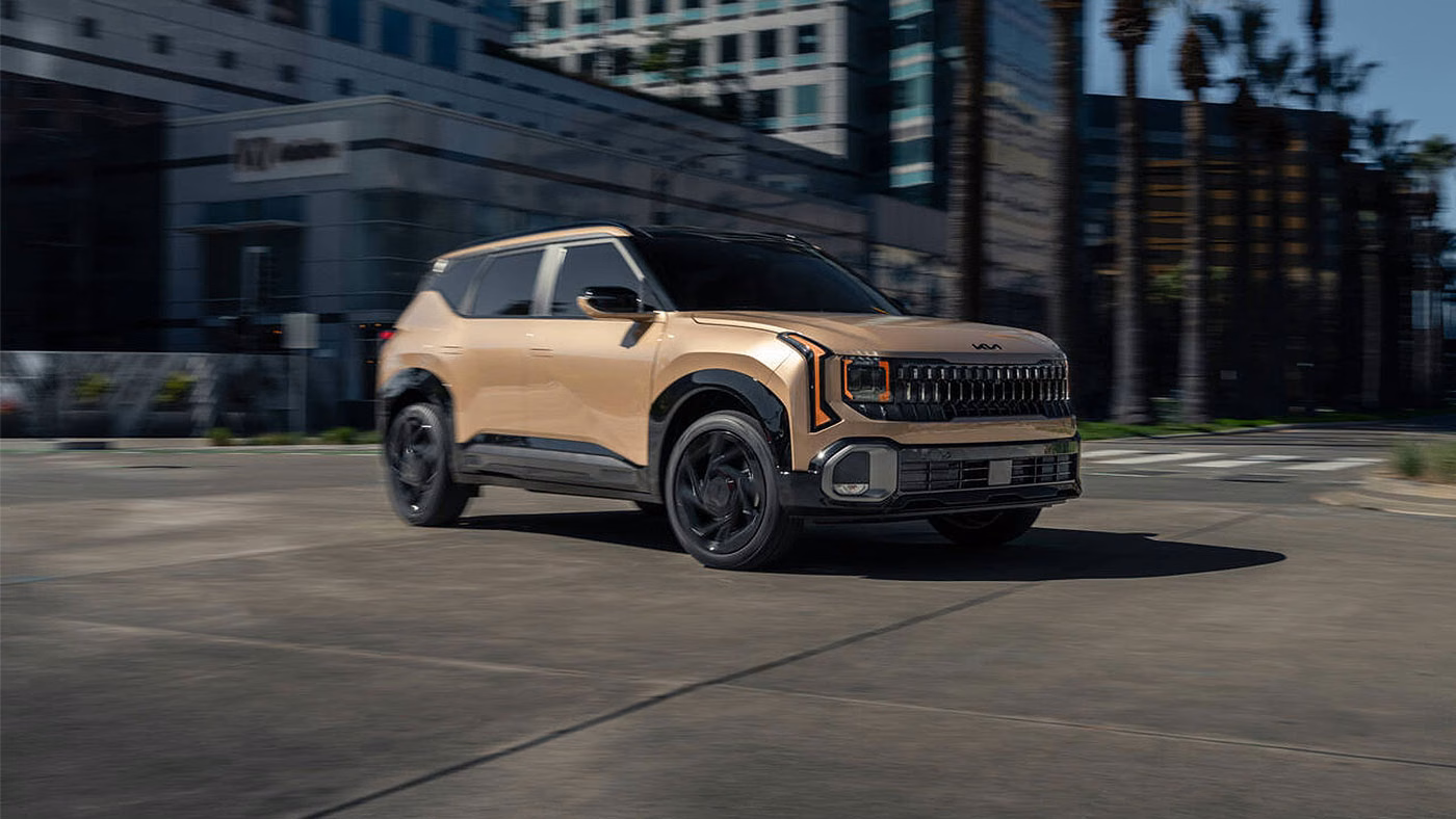 Kia Seltos 2027 beige en mouvement dans une rue urbaine, vu de trois quarts avant