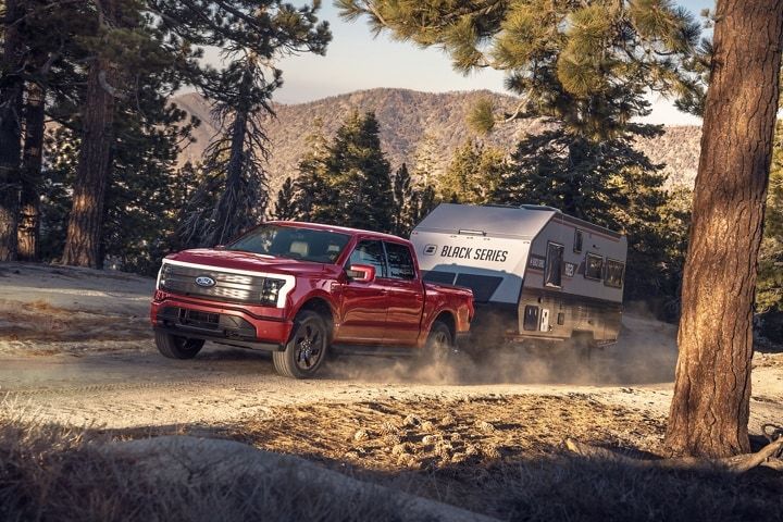 Un Ford F-150 Lightning tirant une roulotte dans une montée.