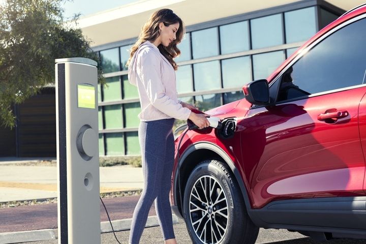 Une femme branche son Ford Escape Hybrid rechargeable.