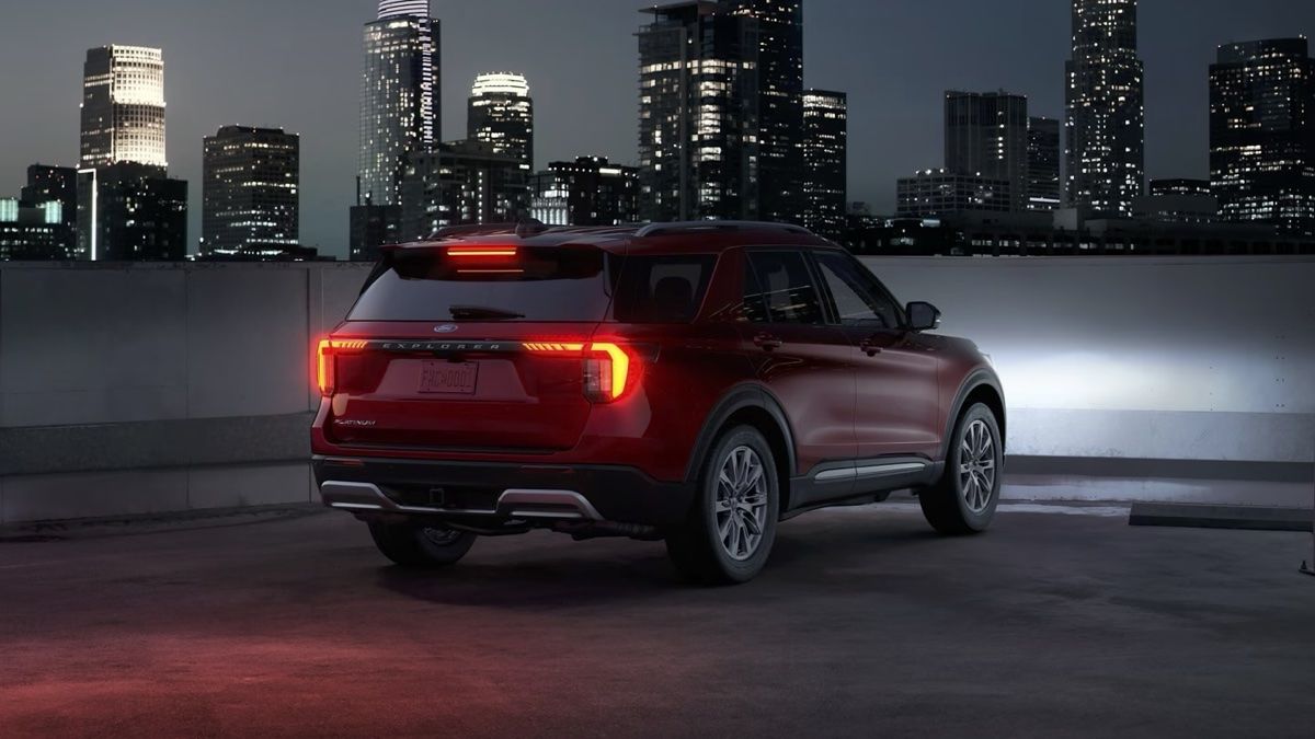 Le Ford Explorer 2025 stationné pour la nuit avec un arrière plan de ville éclairée.