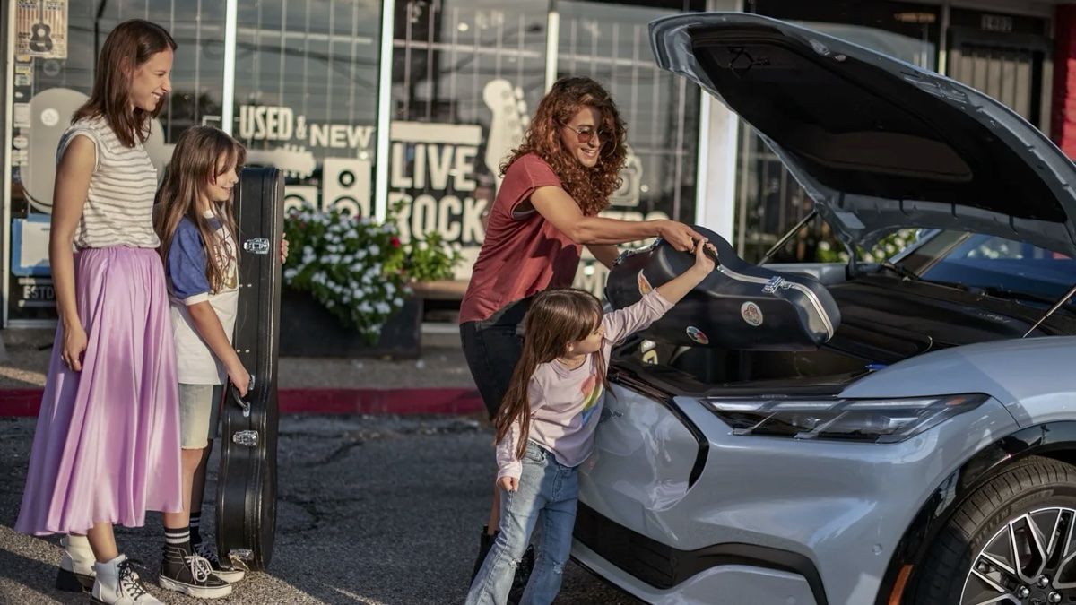 Une famille qui charge des affaires dans le coffre avant de la Ford Mustang Mach-E 2024.