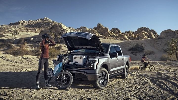 Une famille en train de faire du moto cross à côté de leur F-150 lightning.