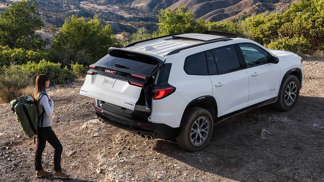 Vue arrière du GMC Acadia 2026 blanc circulant sur une route asphaltée