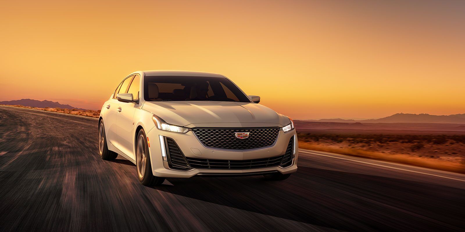 Front 3/4 view of the 2023 Cadillac CT5 being driven on a long road.