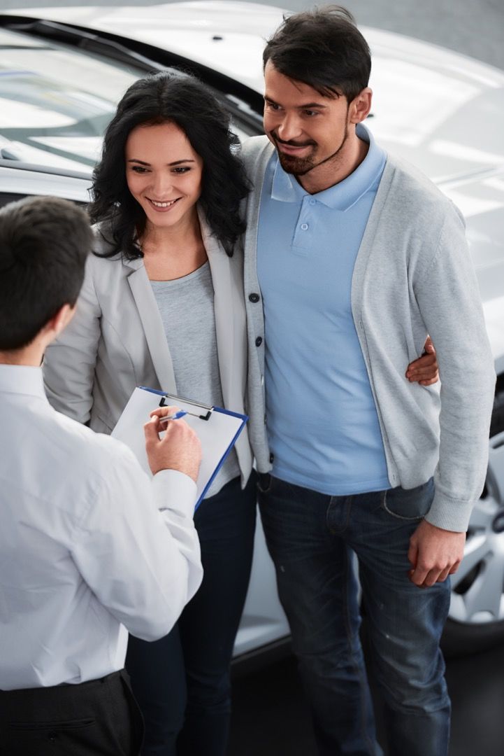 Couple écoutant les conseils d'un vendeur automobile au sujet du financement auto.