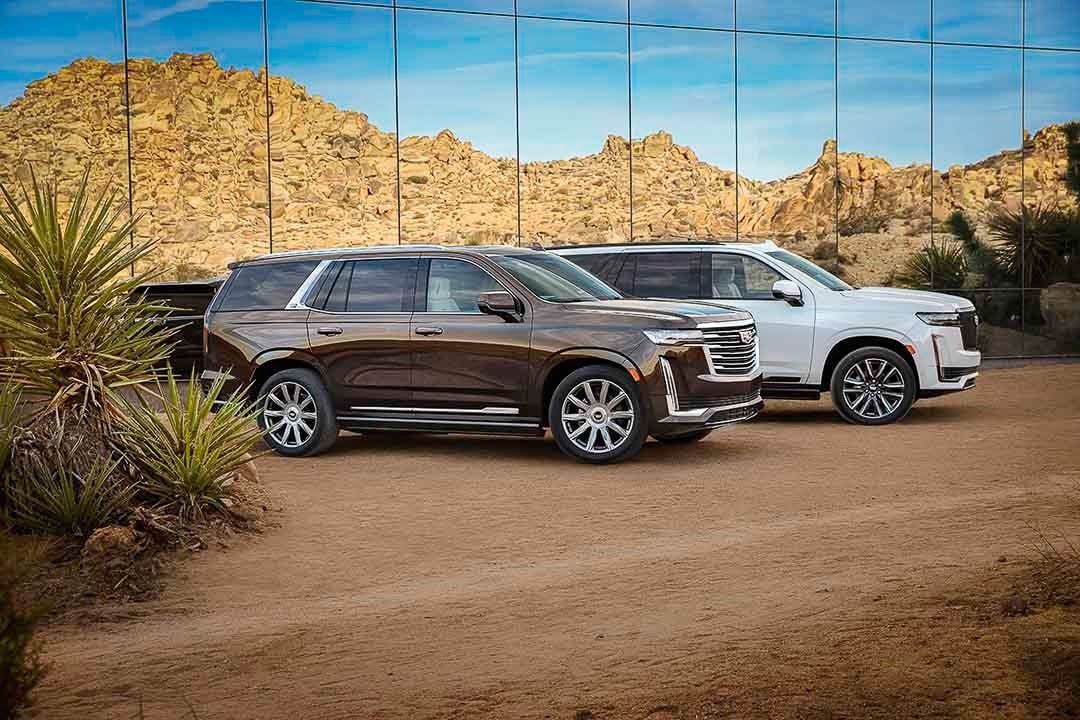 lateral view of two 2022 Cadillac Escalade in front of a mirrored structure
