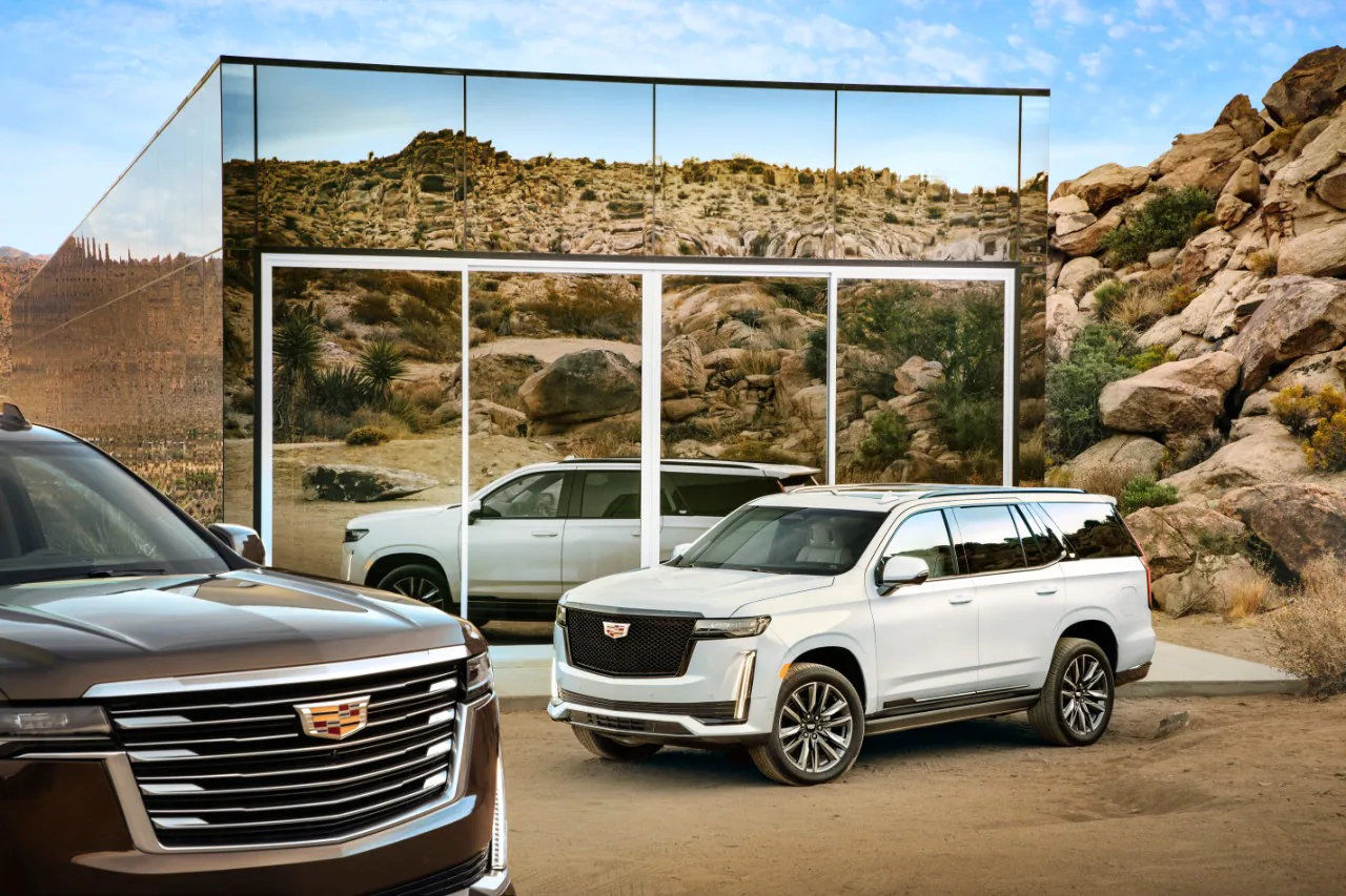 front side view of two 2021 Cadillac Escalade in front of a mirror-covered building