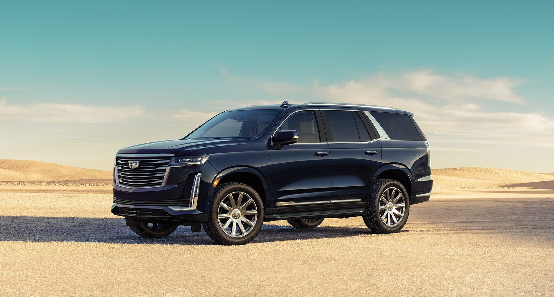 Front 3/4 view of the 2023 Cadillac Escalade Luxury version parked on a deserted lot.