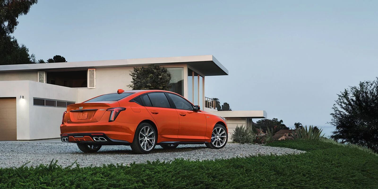 Rear 3/4 view of orange 2023 Cadillac CT5-V Blackwing parked outdoors.