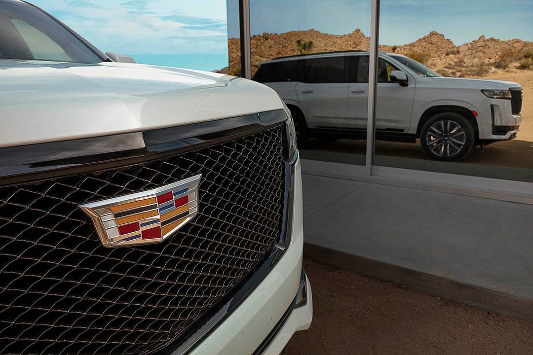 Close up shot of the 2021 Cadillac Escalade front girlle with the reflection of the SUV in a nearby building window 