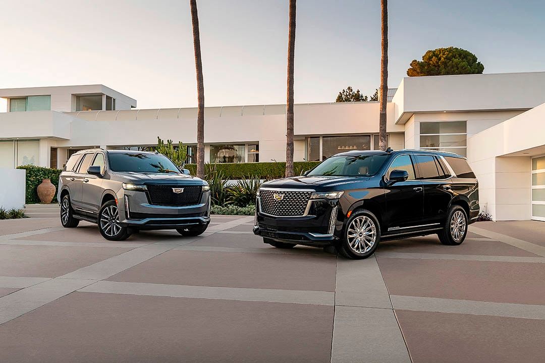 two 2021 Cadillac Escalade parked in front of a house