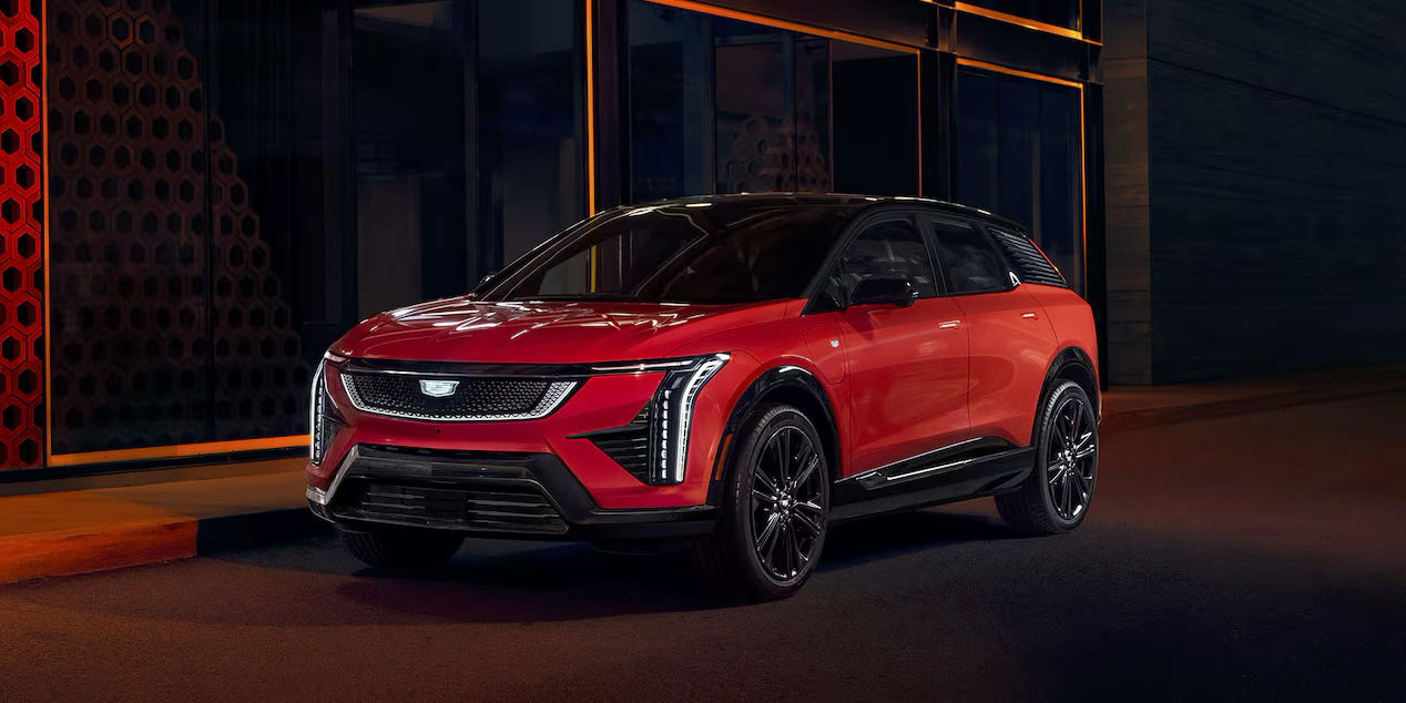 Le Cadillac Optiq 2025 stationné dans la rue pour la nuit sous la lumière des néons.