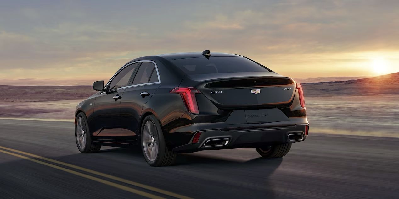 3/4 rear view of the Cadillac CT4 driving down the road at sunset.