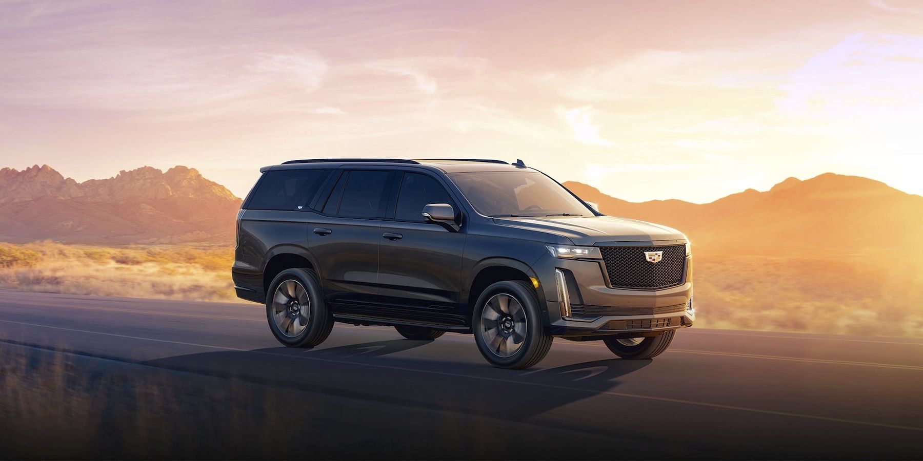 The Cadillac Escalade on the road at sunset.