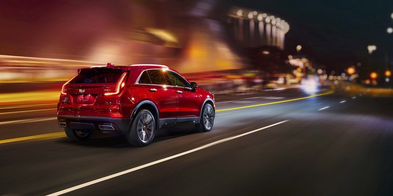 Vue 3/4 arrière de la Cadillac XT4 qui roule en ville la nuit.