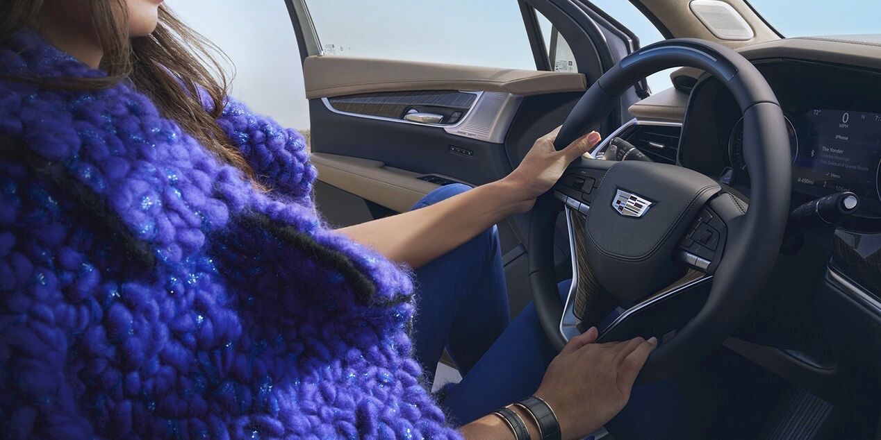 Vue d'une femme au volant de son Cadillac XT6 et sur le design intérieur de la porte.