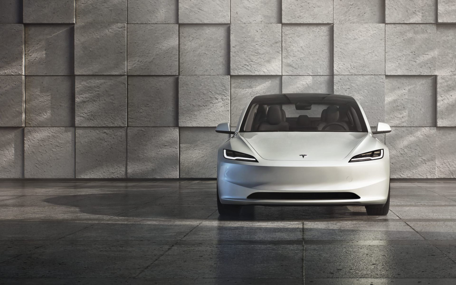 La Tesla Model 3 2024 stationné devant un bâtiment.