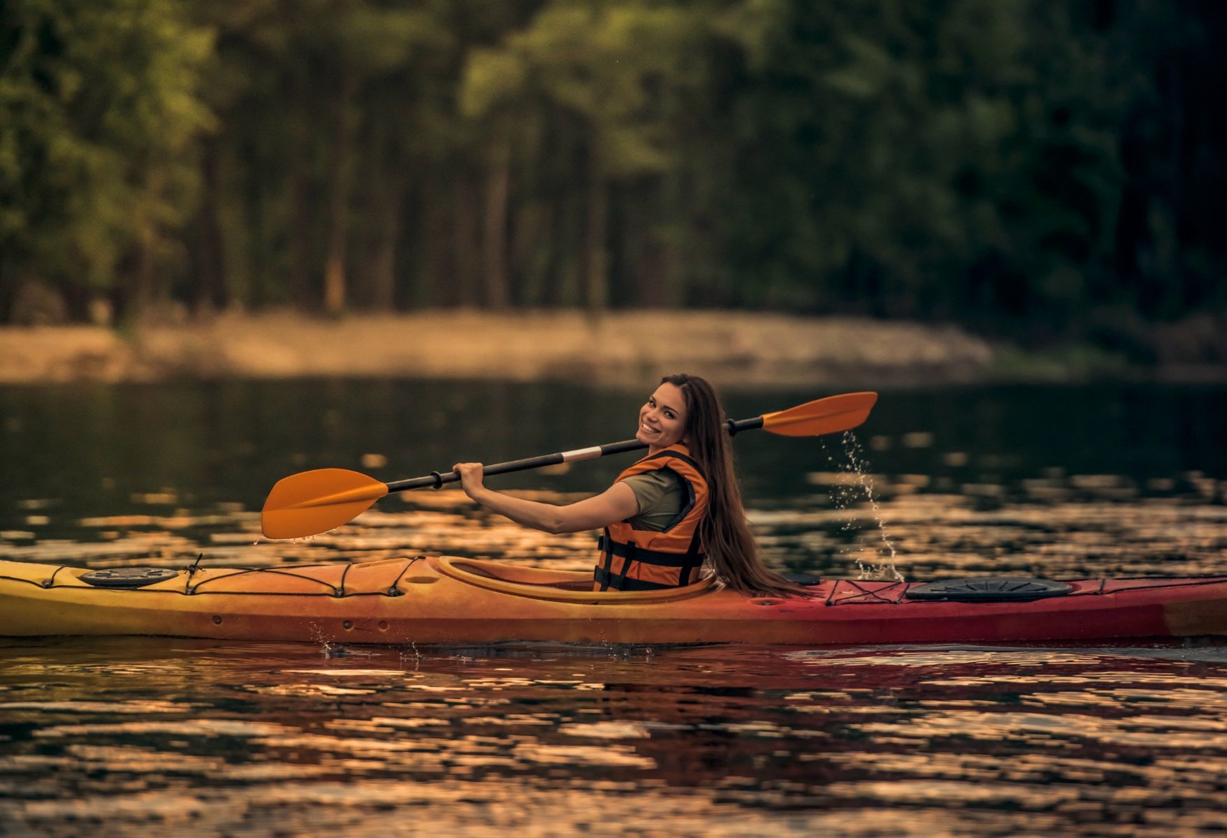 Une femme qui fait du kayak au couché du soleil.