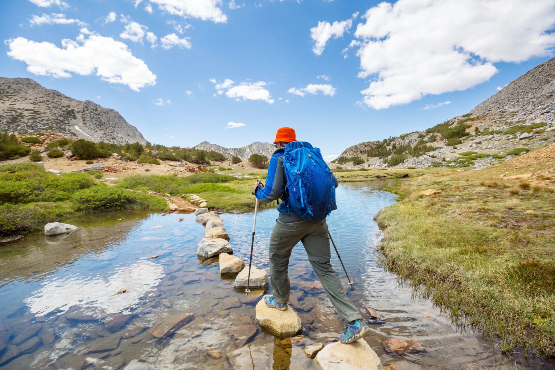 Un homme qui traverse une rivière pendant sa randonnée.