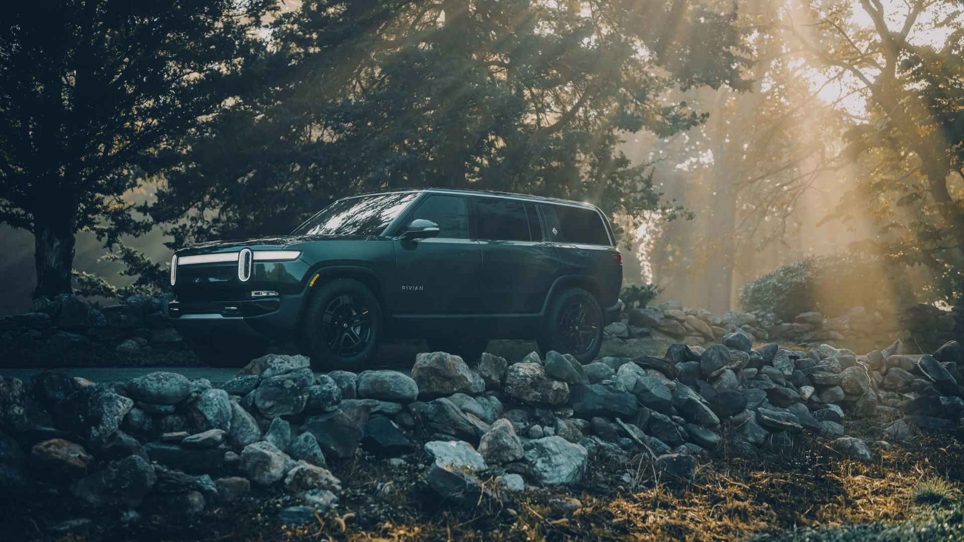 Le Rivian R1S qui roule sur des roches en foret.