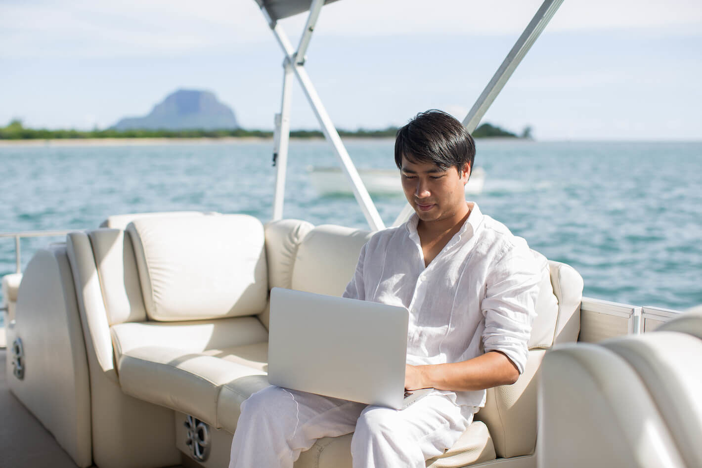 Un homme assis dans son bateau utilisant son laptop.