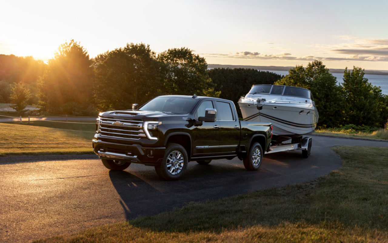 vue latérale avant d'un Chevrolet Silverado 2500 HD 2024 remorquant un bateau sur une route de campagne