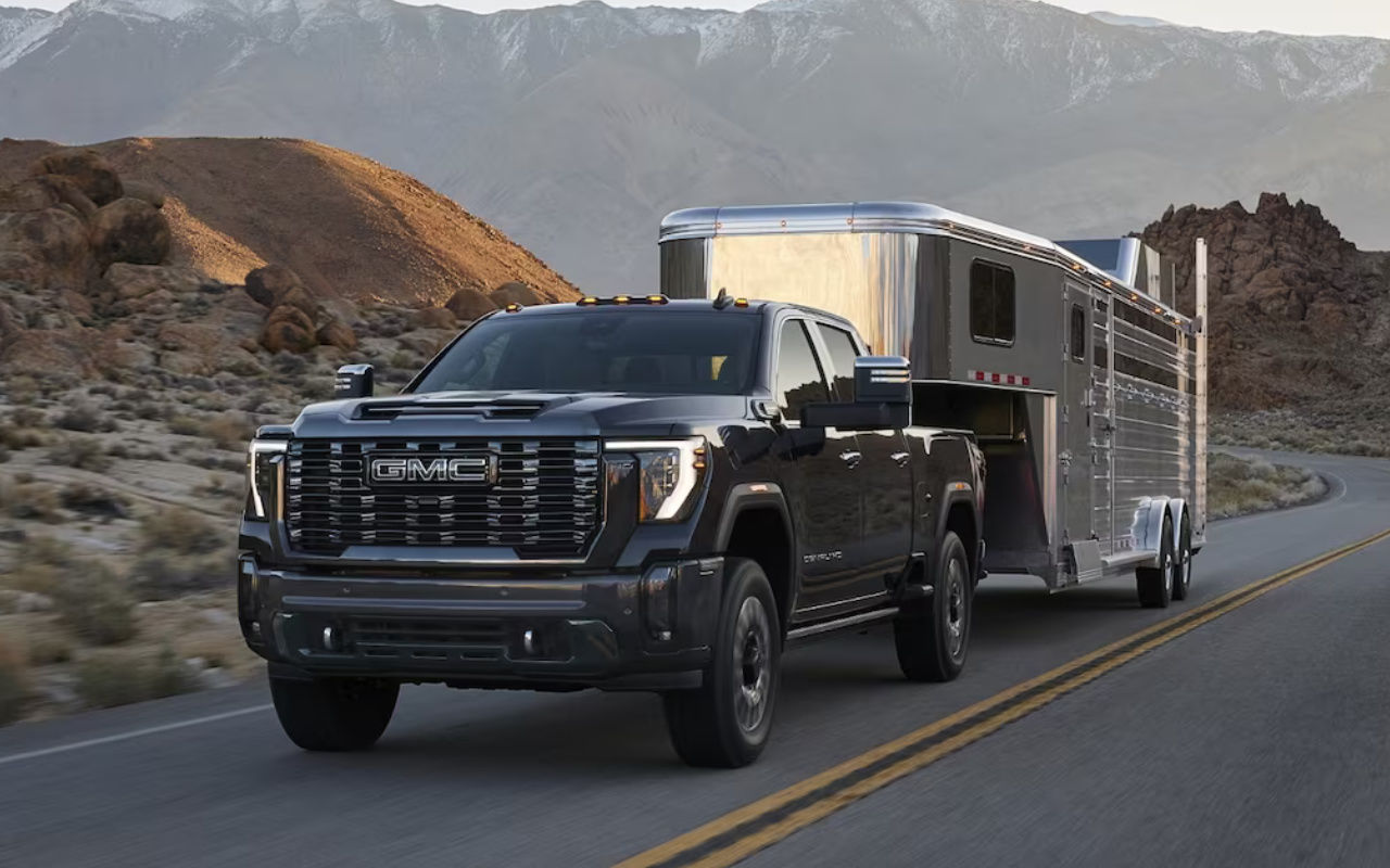 vue latérale avant d'un GMC Sierra 2500 2024 trainant une remorque sur une route de campagne