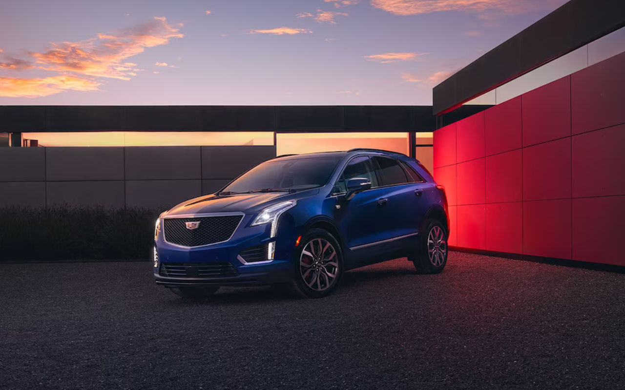 front side view of a 2024 Cadillac XT5 with turned on headlights at dusk