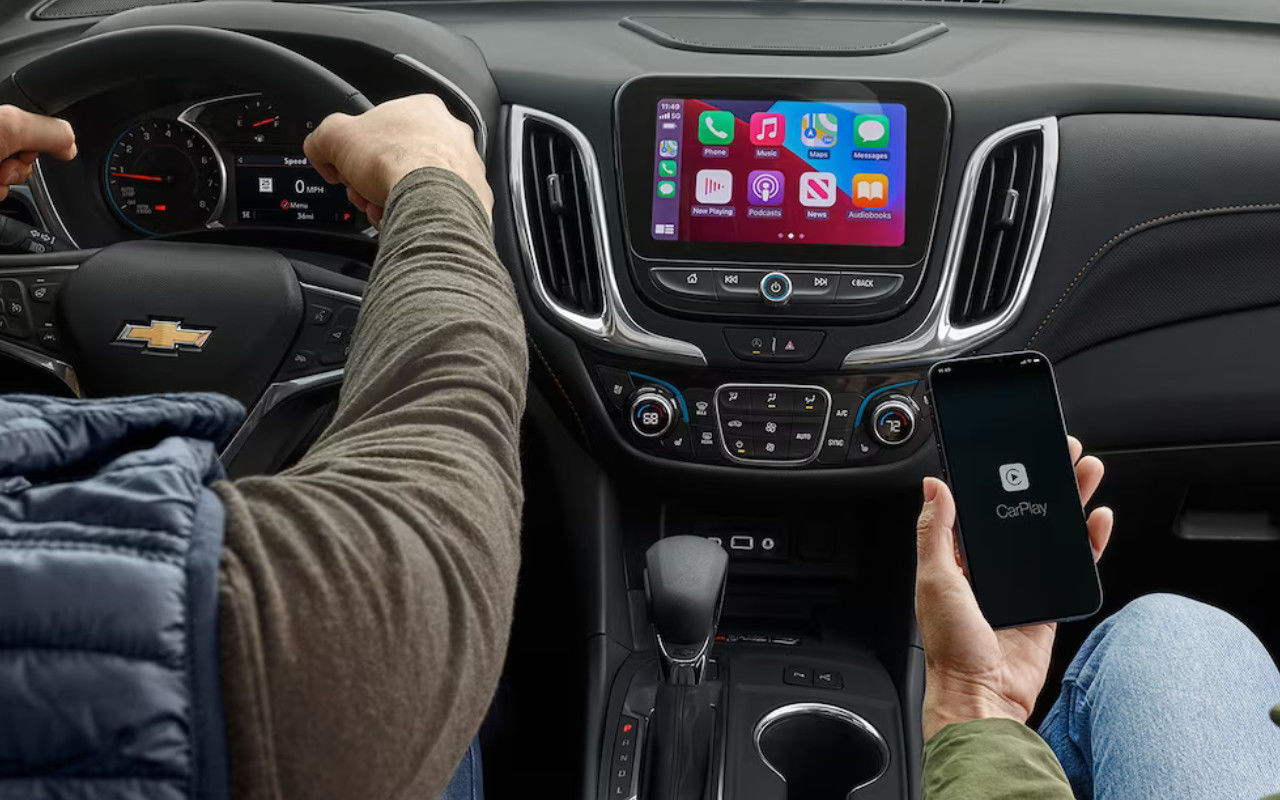 vue du tableau de bord d'une Chevrolet Equinox 2024 et une personne qui y connecte son téléphone intelligent