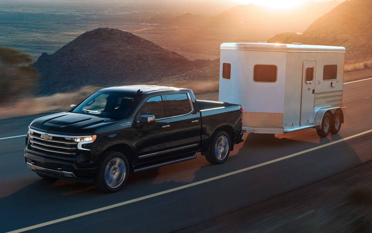 vue latérale avant d'une Chevrolet Silverado 2024 remorquant une roulotte sur une route de montagne