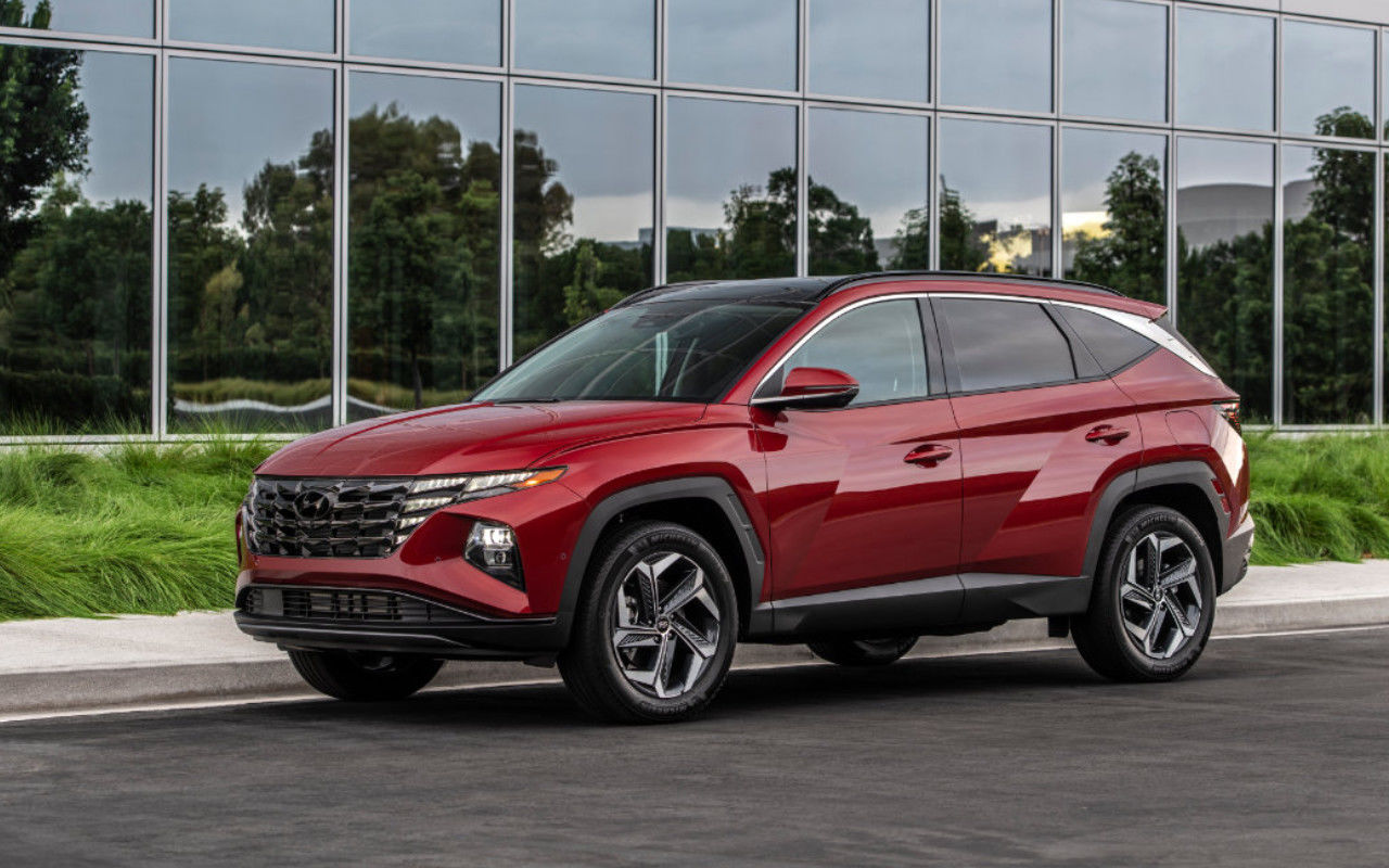 vue latérale avant d'une Hyundai Tuscon 2024 garé devant un batiment vitré