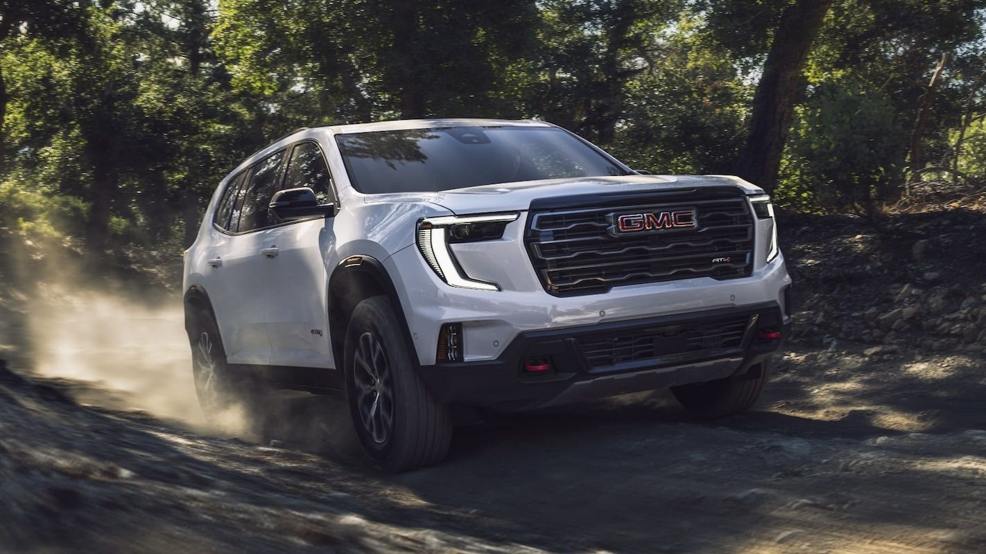 Un GMC Acadia qui roue sur un chemin de terre en forêt.