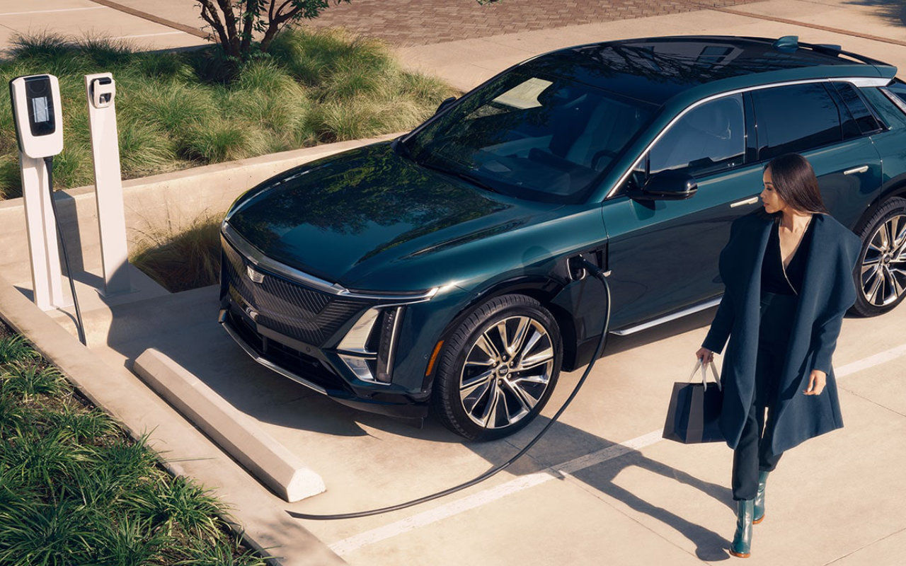 vue latérale avant d'une Cadillac Lyriq 2025 branché à une borne de recharge près de sa conductrice