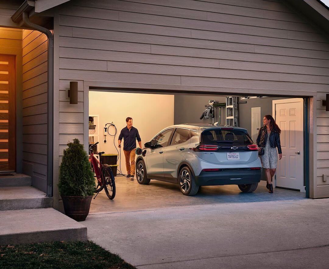 Homme s'apprêtant à charger sa Chevrolet Bolt EV 2022 à domicile pendant que sa femme le regarde