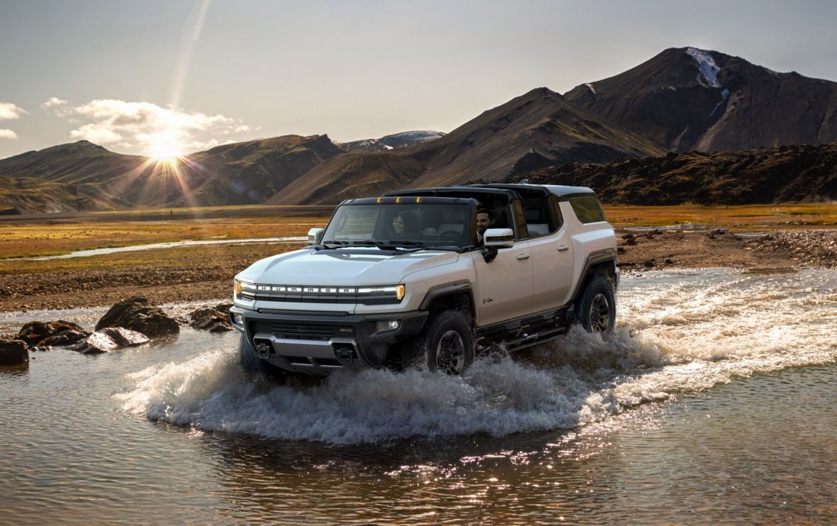 Le pickup Hummer EV 2023 blanc roulant dans un étang d'eau incluant les montagnes en arrière-plan