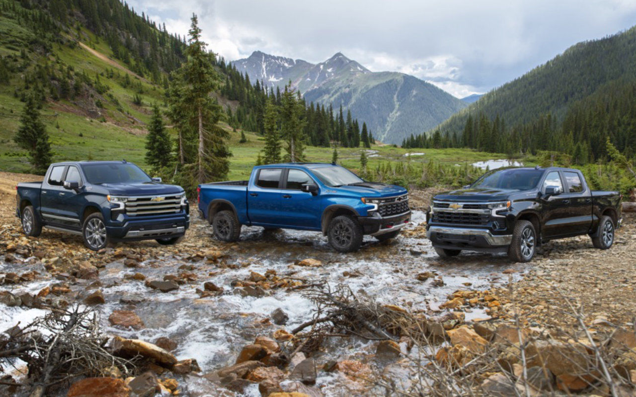 vue latérale avant d'un trio de camions Chevrolet Silverado 2023 en montagne