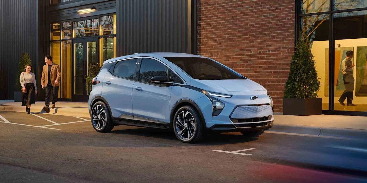 Un couple sortant d'un immeuble se dirige vers leur nouvelle Chevrolet Bolt EV 2021 finançée