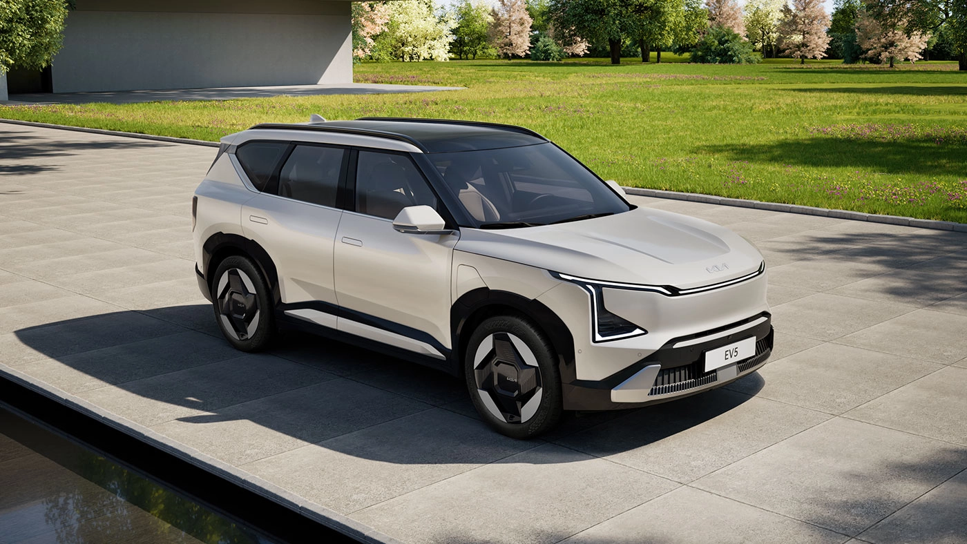 3/4 front and side view of the 2026 Kia EV5 in Silver Ivory on cobblestones by the water