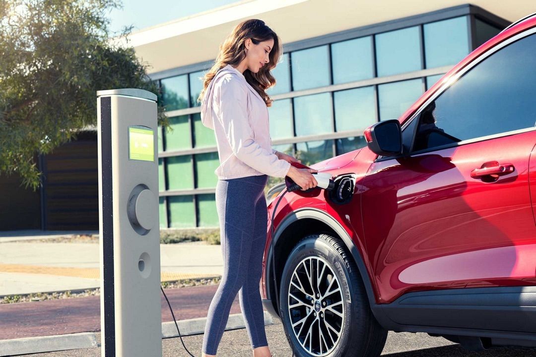 Une femme rechargeant la batterie du Ford Escape hybride rechargeable 2023.